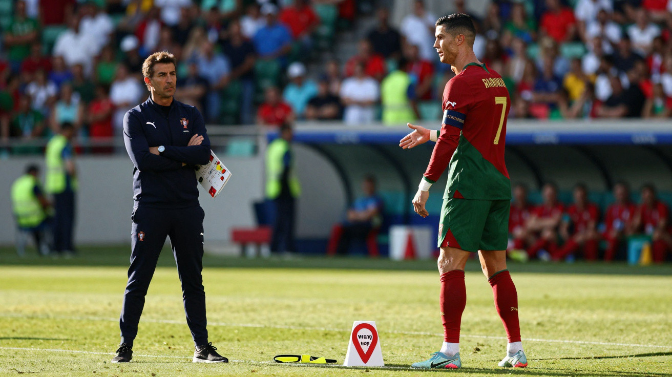 Treinador português observando jogador Cristiano Ronaldo em campo durante partida de futebol.